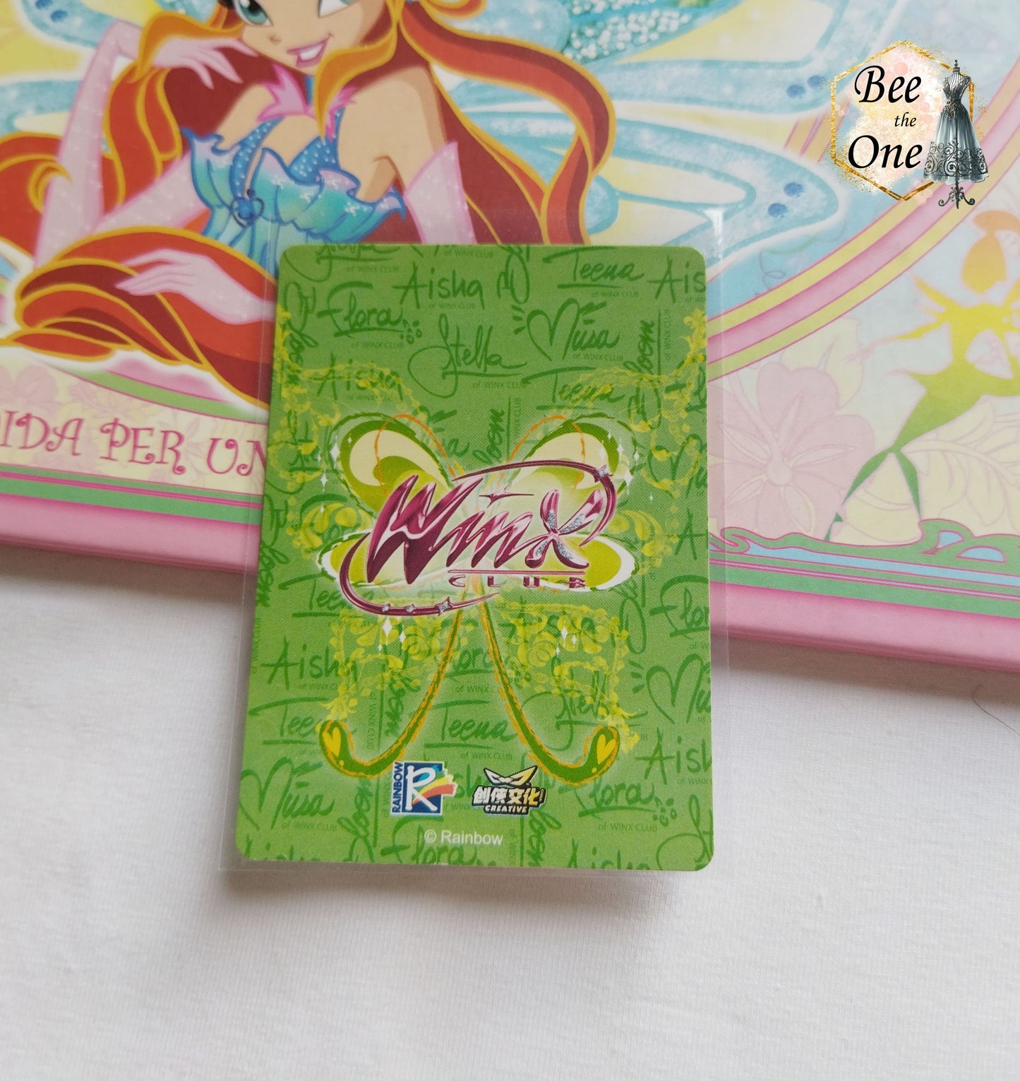 Cartes à collectionner inspirées de l'univers magique de Winx Club. La carte est ornée de motifs floraux, potion et de détails étincelants, évoquant la magie et l'aventure. Gros plan dos