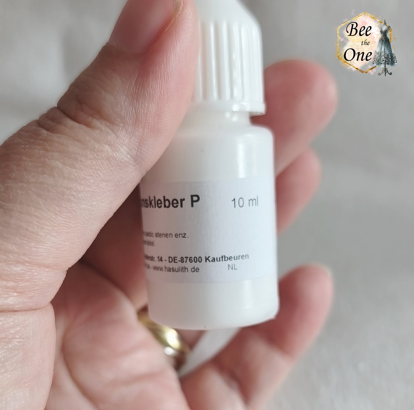 Flacon applicateur de colle Hasulith Dispersion de 10 ml avec bouchon blanc, sur un fond blanc texturé. Gros plan côté
