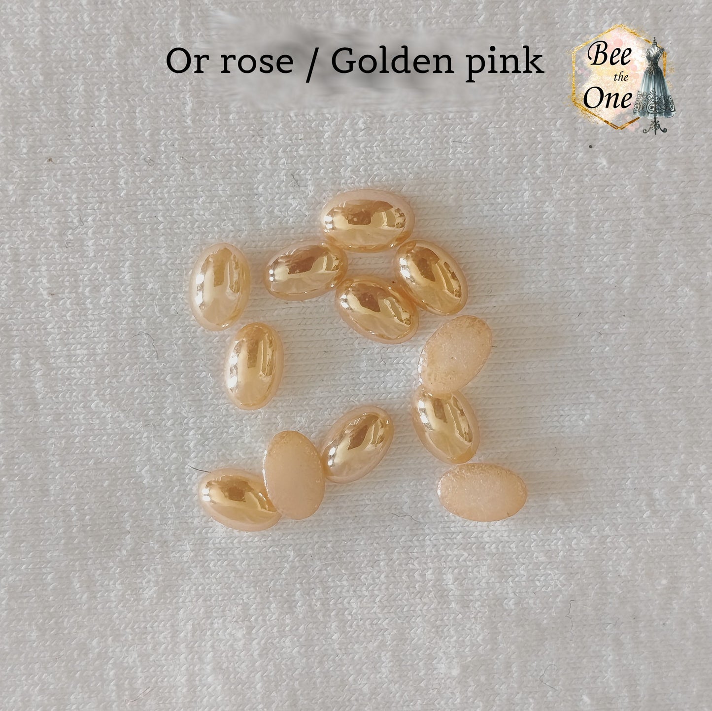 Mini cabochons ovales lisses de 6x4 mm en acrylique or rose, posés sur un fond blanc.
