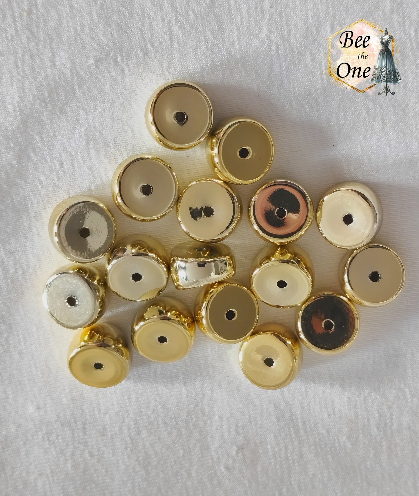 Perles tubes séparateurs incurvées en acrylique doré avec finition métallisée brillante et effet miroir, mesurant 11 mm, disposées sur un fond blanc texturé.