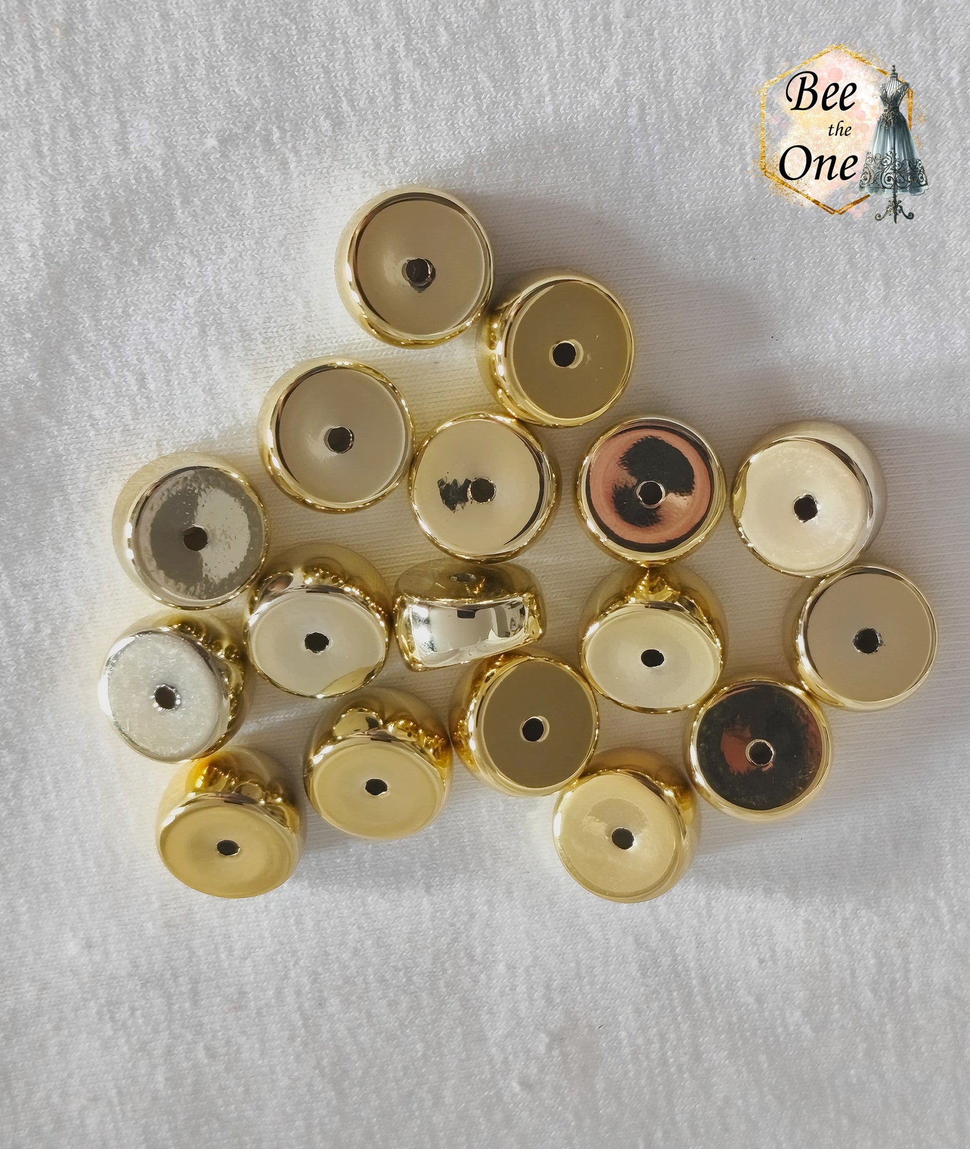 Perles tubes séparateurs incurvées en acrylique doré avec finition métallisée brillante et effet miroir, mesurant 11 mm, disposées sur un fond blanc texturé.