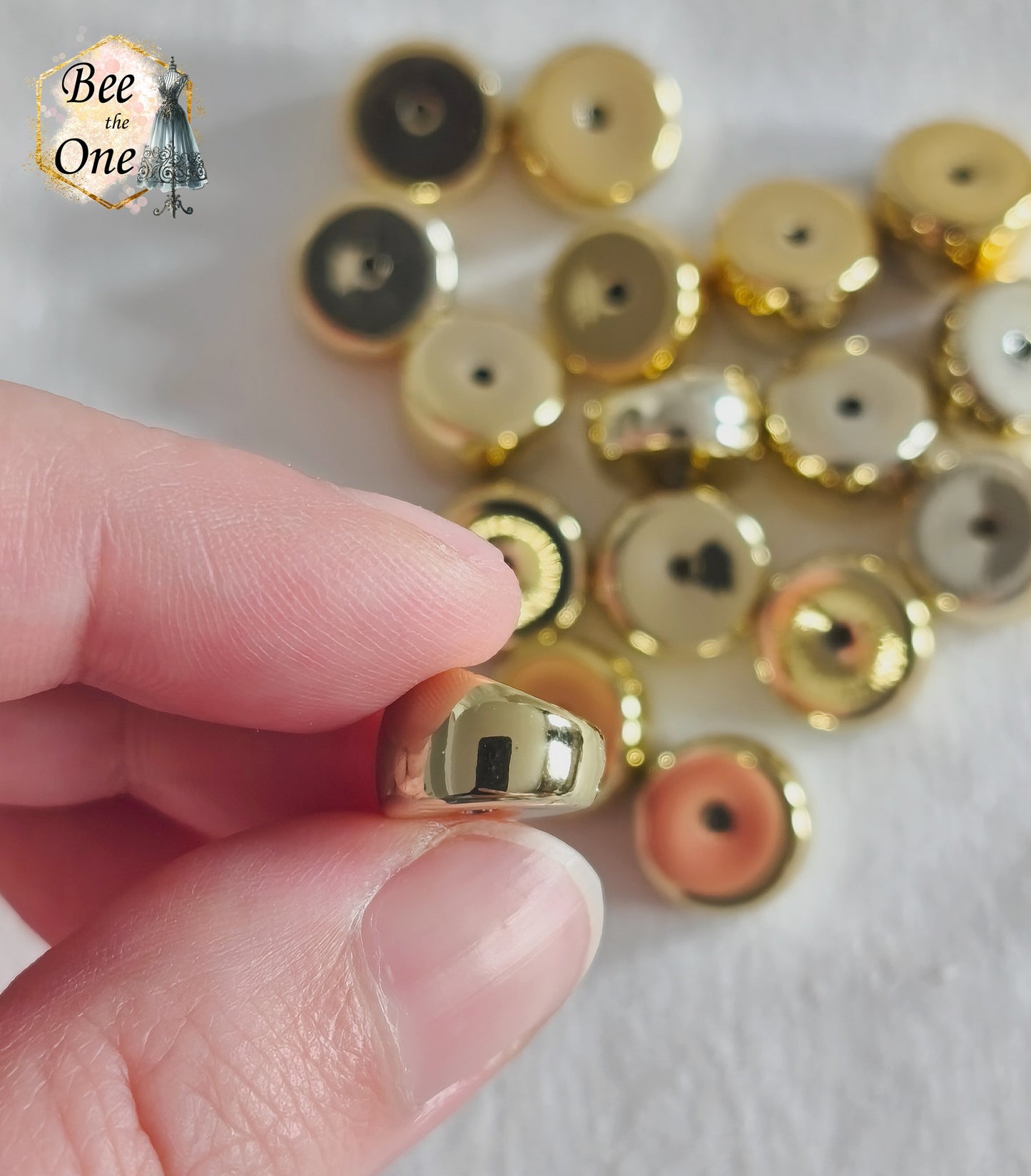 Perles tubes séparateurs incurvées en acrylique doré avec finition métallisée brillante et effet miroir, mesurant 11 mm, disposées sur un fond blanc texturé. Gros plan sur une perle