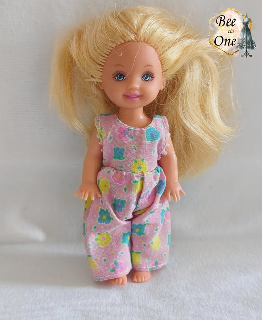 Combinaison salopette rose à motifs de petites fleurs multicolores (bleu, jaune, vert, rose) pour poupée Shelly (Kelly), issue du coffret Barbie Dentiste 1997 de Mattel, portée par une petite poupée blonde sur fond blanc.