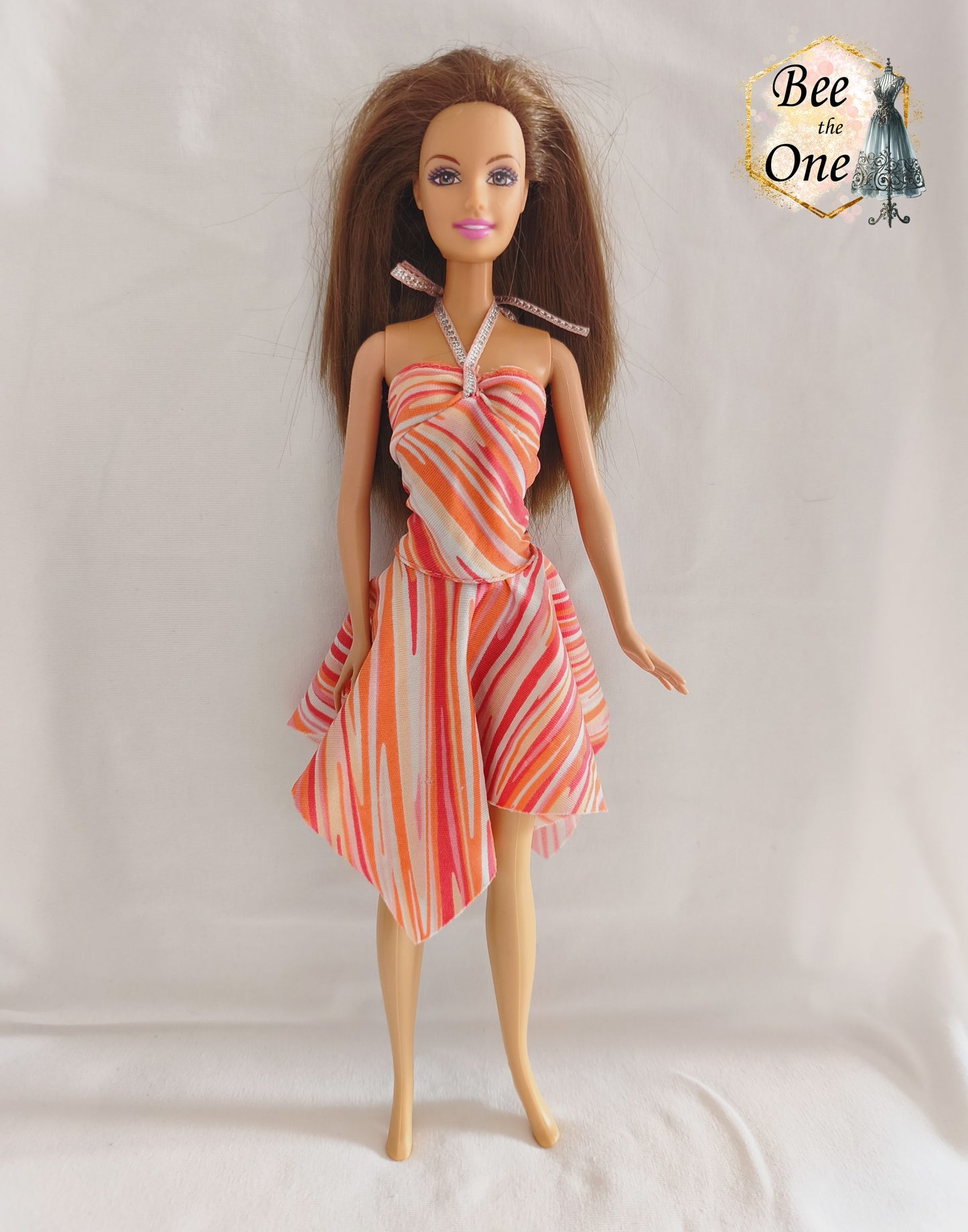 Robe asymétrique pour poupée mannequin Barbie Fashion Fever 2005, dos-nu à motifs géométriques corail, rose et orange avec attache argentée, présenté sur mannequin et fond blanc.