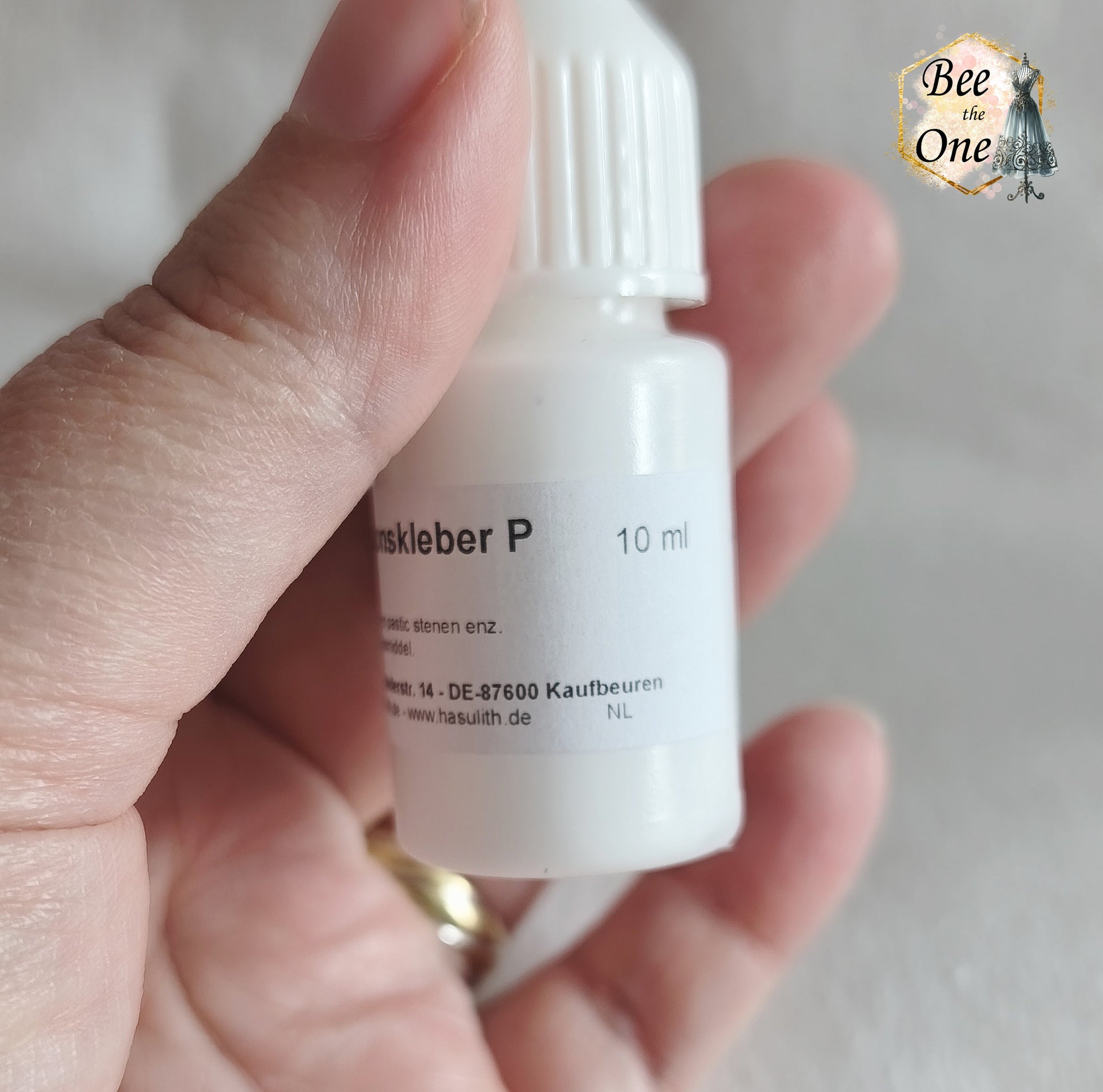 Flacon applicateur de colle Hasulith Dispersion de 10 ml avec bouchon blanc, sur un fond blanc texturé. Gros plan côté