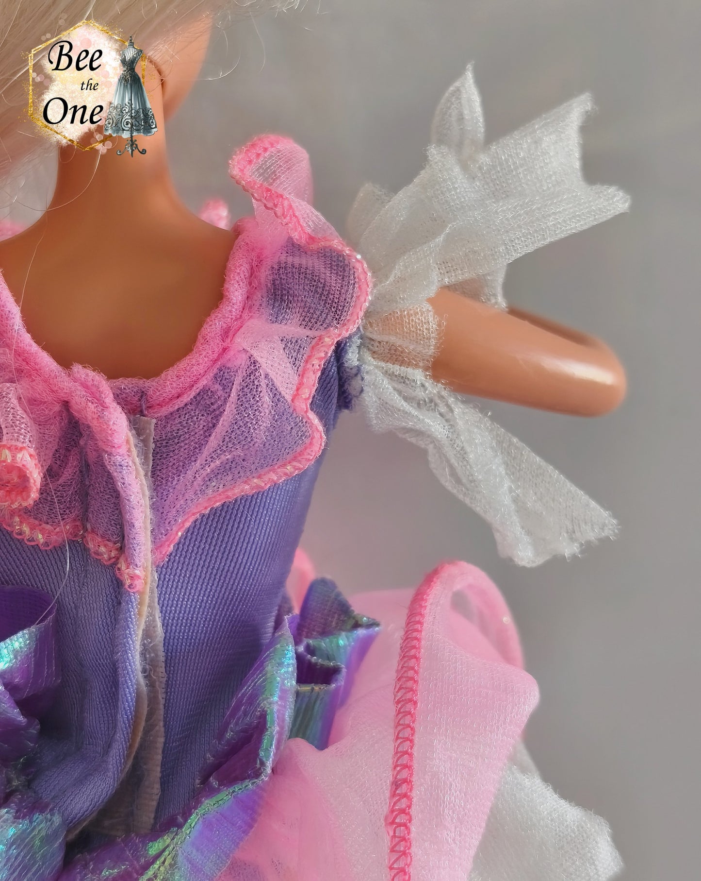 Robe de poupée Barbie Toothfairy 1994, édition spéciale exclusive Walmart, portée par une poupée blonde sur fond blanc. Le body est mauve et le tutu rose. À noter : les parties blanches en tulle sur les manches et sous le tutu sont très déchirées et endommagées. Gros plan manche droite de dos