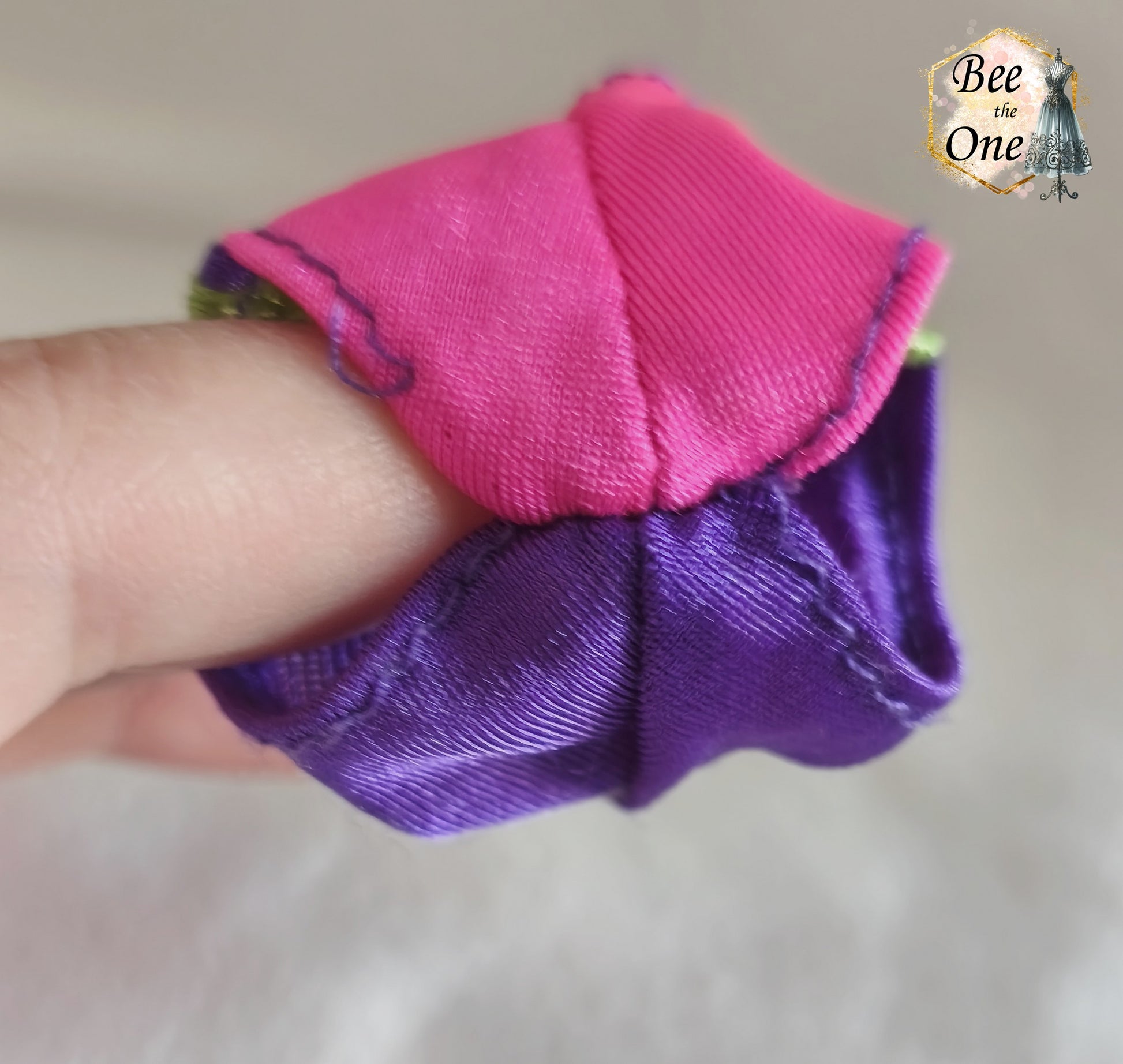 Culotte de maillot de bain rose fuchsia avec rayures latérales vert fluo et violettes, vêtement d'origine pour poupée Barbie Surf City 2000, portée par une poupée brune sur fond blanc. Gros plan entrejambe