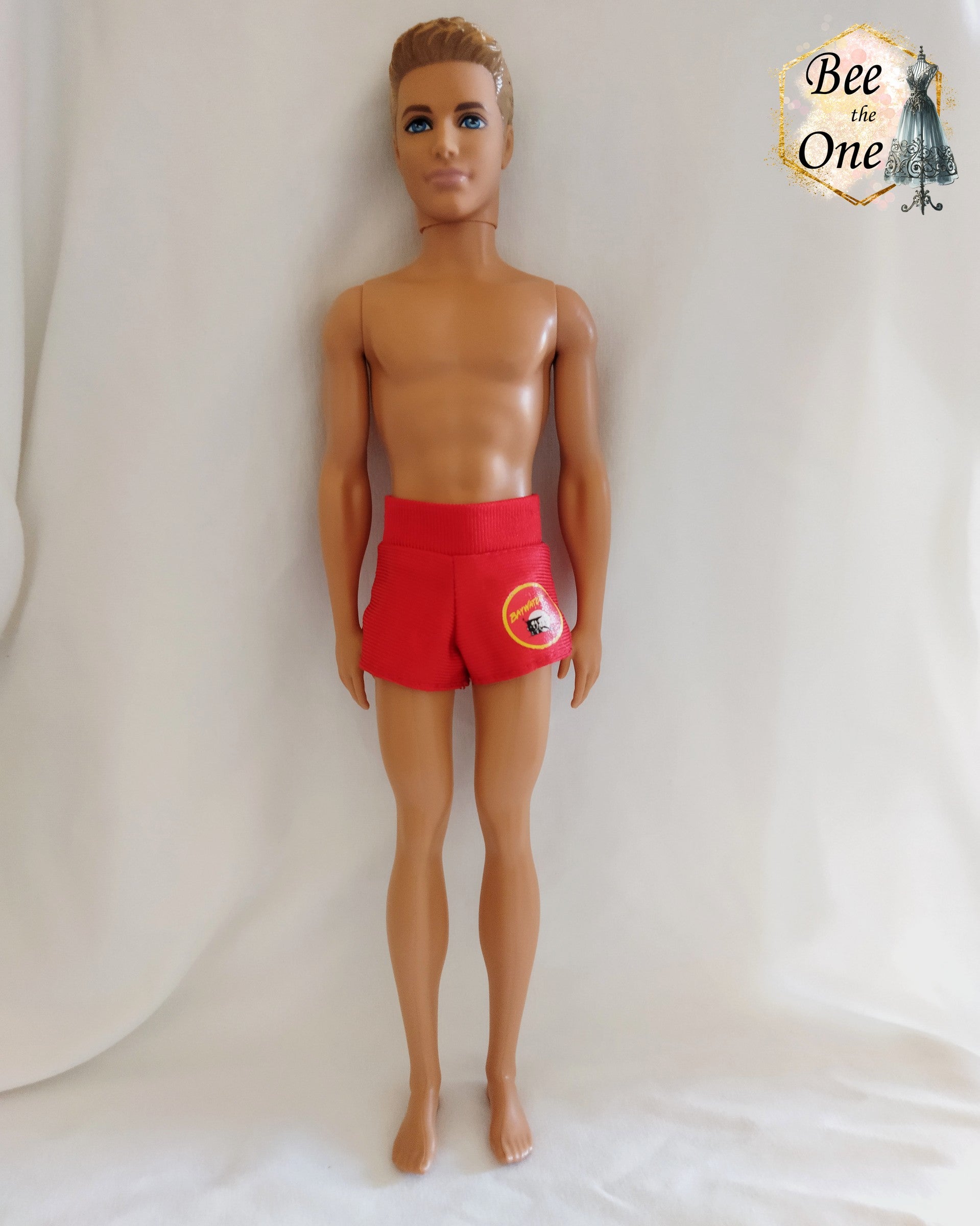 Short de plage pour poupée Ken, rouge avec un patch Baywatch sur le côté. 