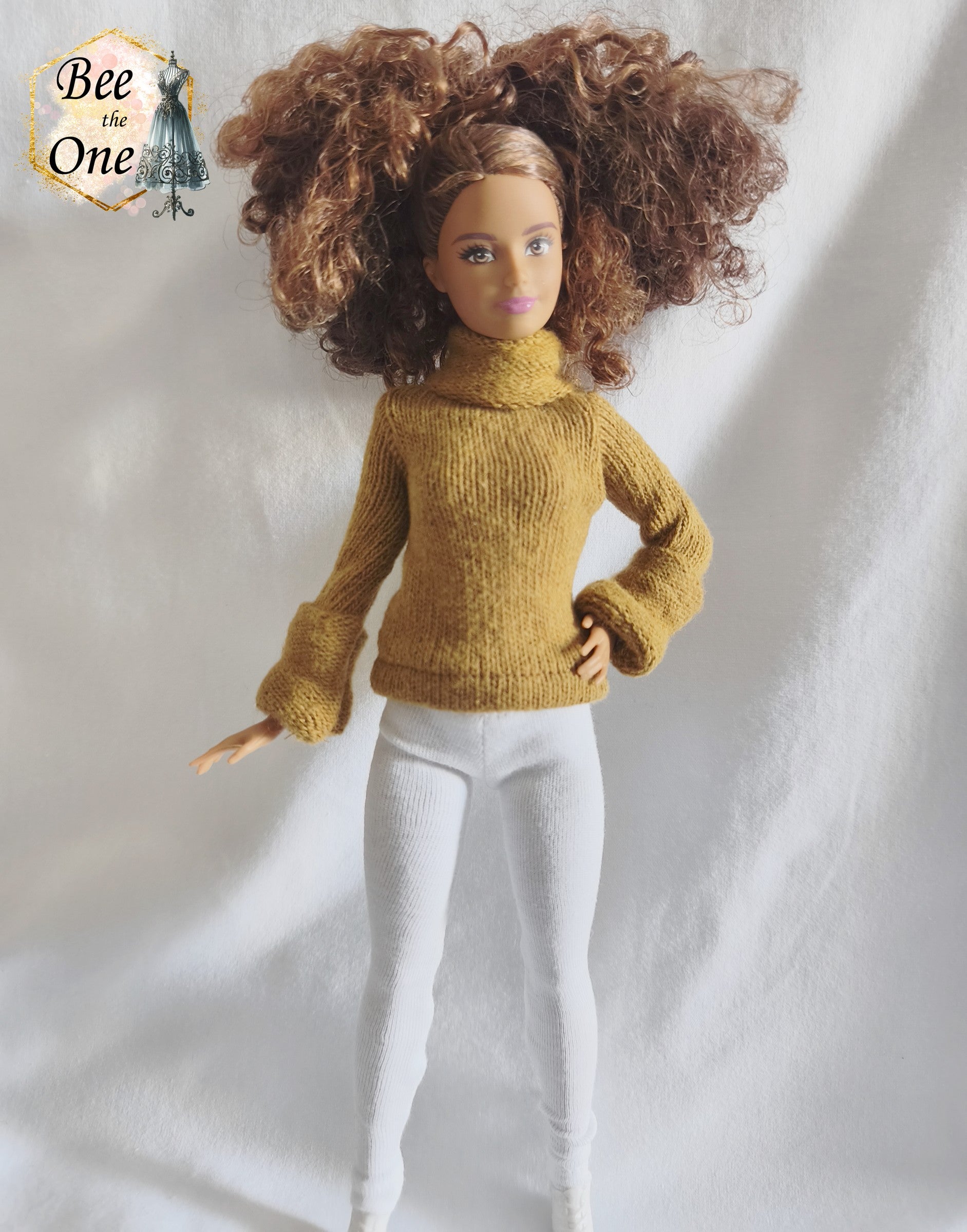 Pull à col roulé fait main en maille fine couleur marron argile, création artisanale ajustée spécialement pour poupée Barbie morphologie Petite, porté avec un legging blanc sur fond blanc.