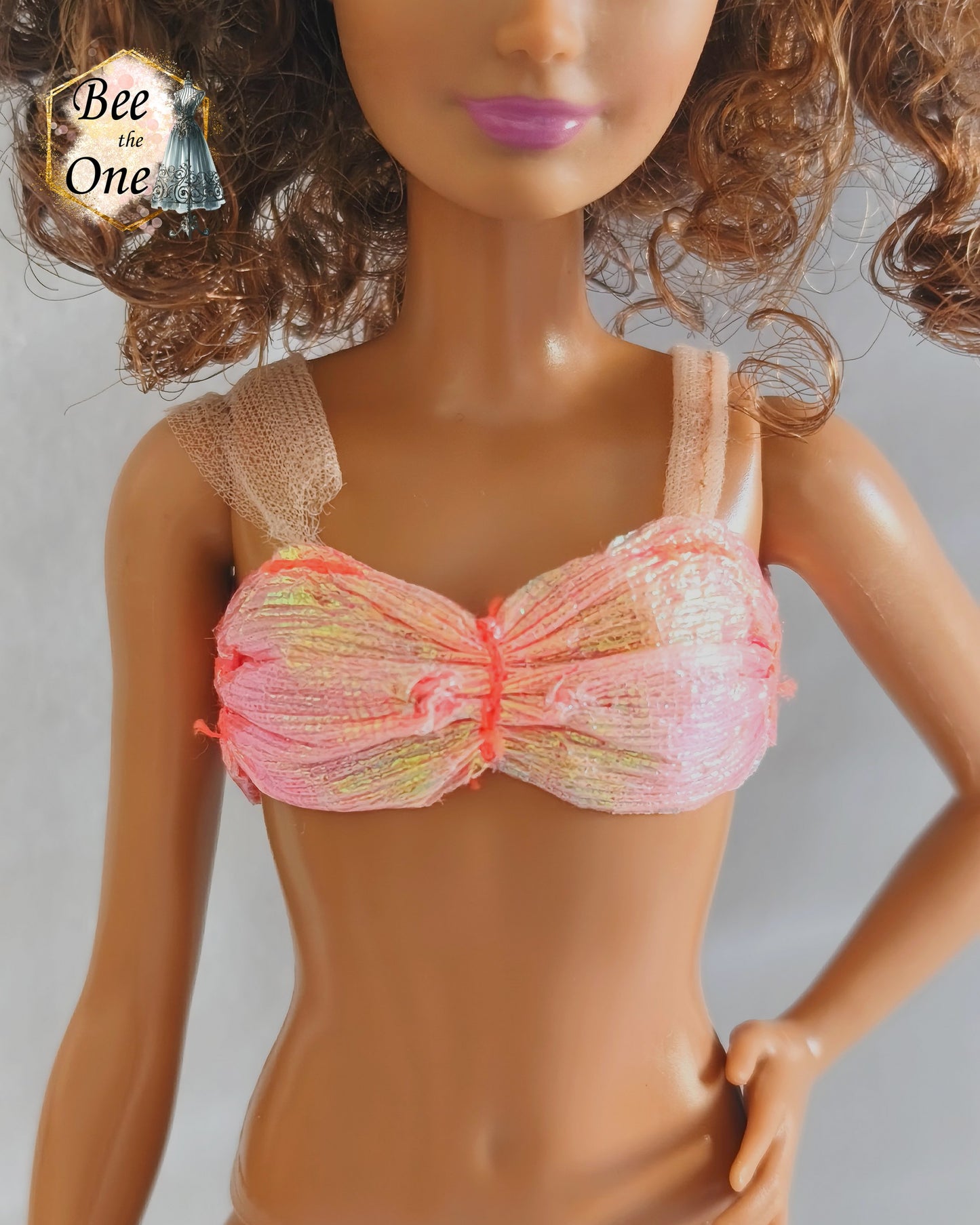 Brassière de bikini bustier rose pailleté et irisé pour poupée Skipper Mermaid & Sea Twins 1993, portée par une poupée brune sur fond blanc. Gros plan devant