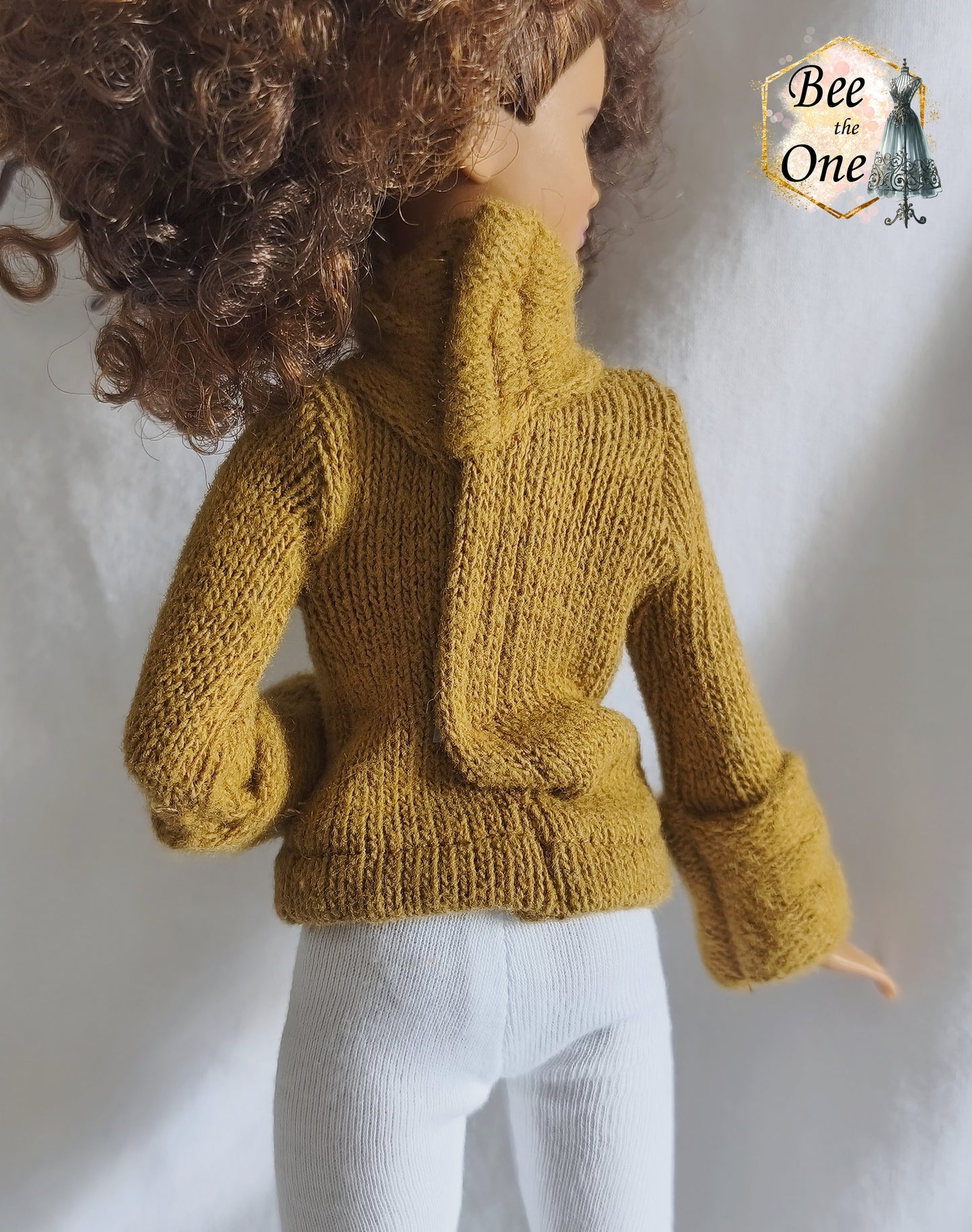 Pull à col roulé fait main en maille fine couleur marron argile, création artisanale ajustée spécialement pour poupée Barbie morphologie Petite, porté avec un legging blanc sur fond blanc. Gros plan dos