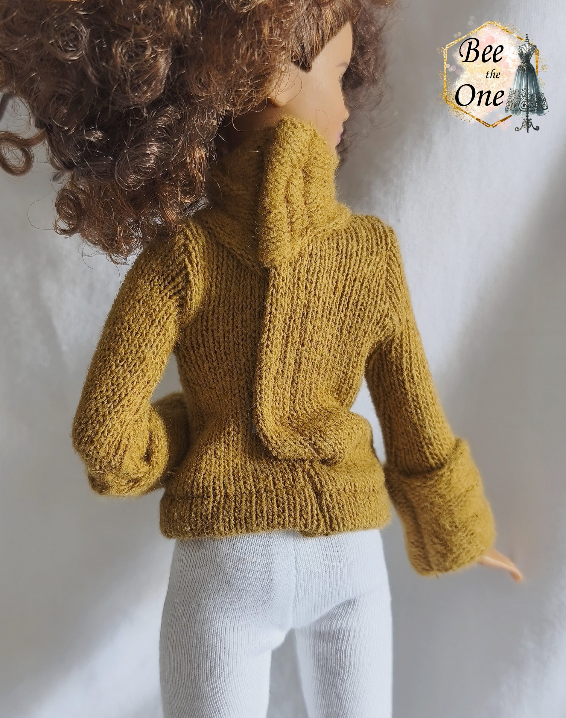 Pull à col roulé fait main en maille fine couleur marron argile, création artisanale ajustée spécialement pour poupée Barbie morphologie Petite, porté avec un legging blanc sur fond blanc. Gros plan dos