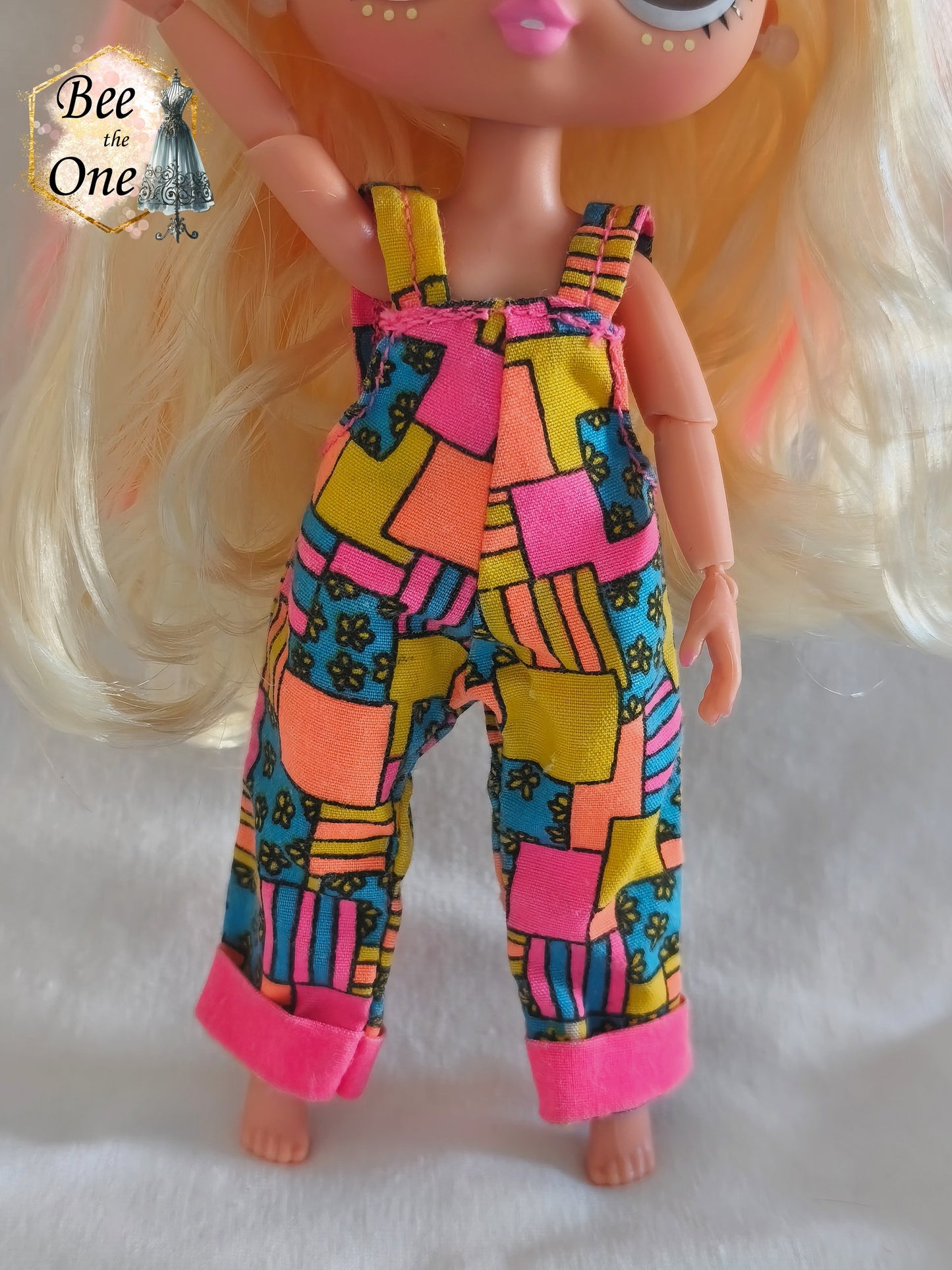 Salopette vintage Sindy & Cyclin Sam Hasbro 1996 à motifs patchwork colorés (rose, orange, jaune, bleu), portée par une poupée LOL OMG Tween sur fond blanc. Gros plan devant
