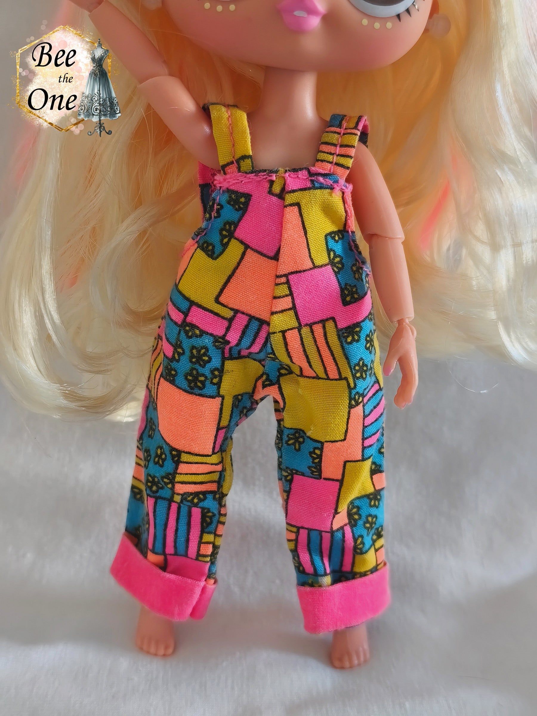 Salopette vintage Sindy & Cyclin Sam Hasbro 1996 à motifs patchwork colorés (rose, orange, jaune, bleu), portée par une poupée LOL OMG Tween sur fond blanc. Gros plan devant