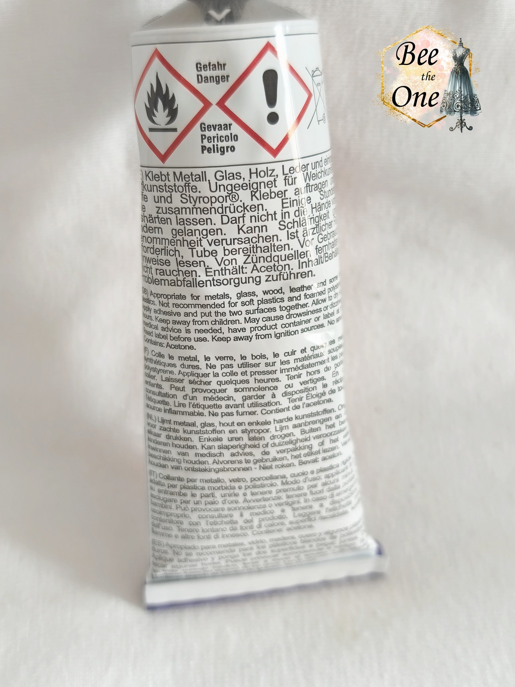 Un tube de colle Hasulith classique de 30 ml (27g) dans son emballage d'originerouge, violet et blanc, posé sur un fond blanc texturé. Gros plan dos