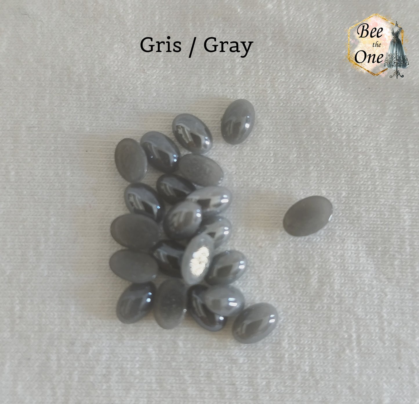 Mini cabochons ovales lisses de 6x4 mm en acrylique gris, posés sur un fond blanc.