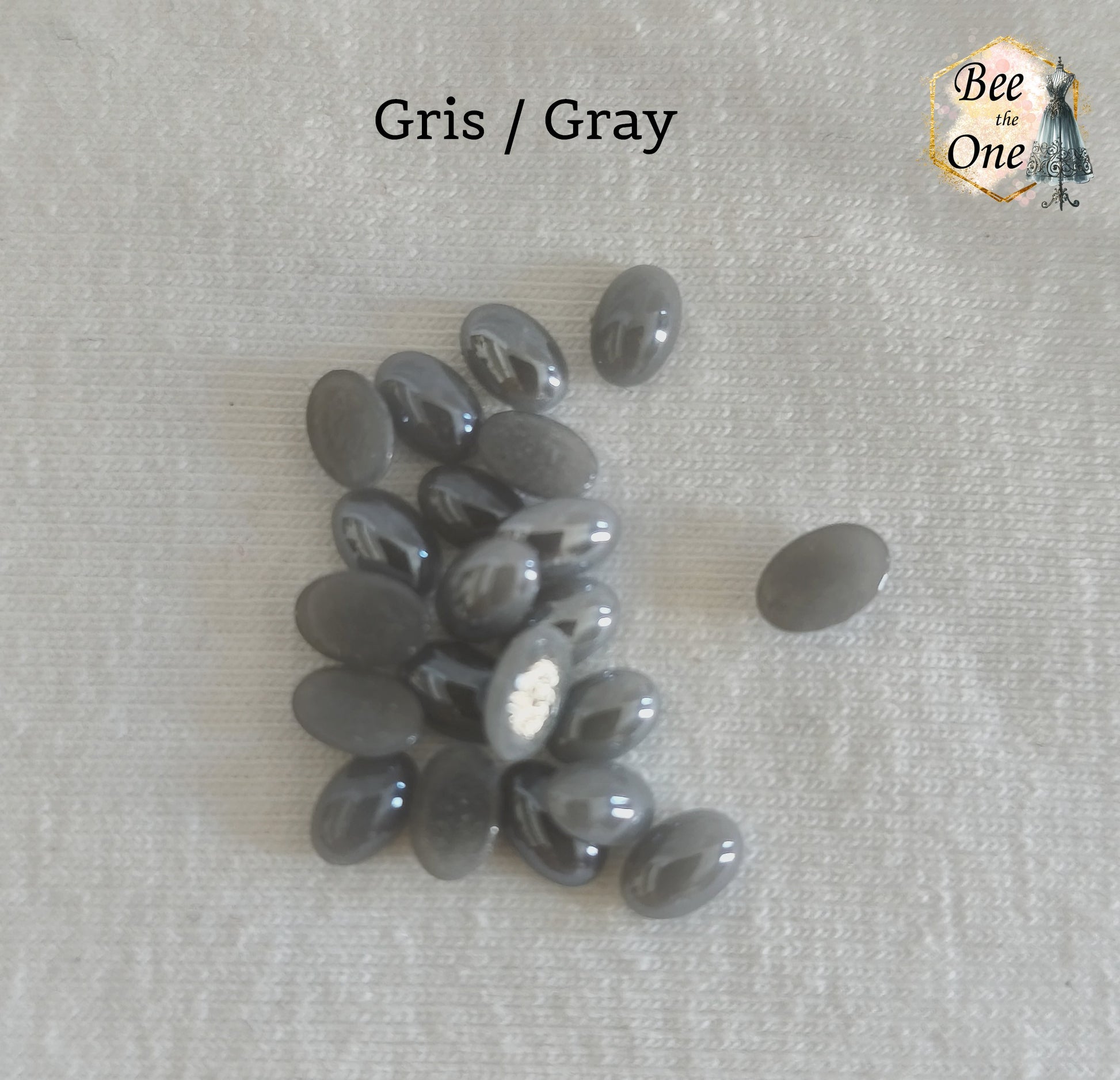 Mini cabochons ovales lisses de 6x4 mm en acrylique gris, posés sur un fond blanc.
