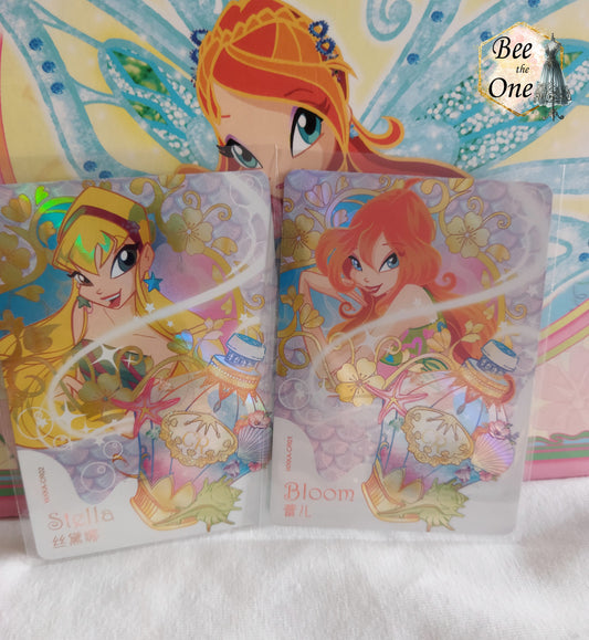 Cartes à collectionner inspirées de l'univers magique de Winx Club, mettant en scène Stella et Bloom dans un style coloré et féerique. Les cartes sont ornées de motifs floraux, potion et de détails étincelants, évoquant la magie et l'aventure.