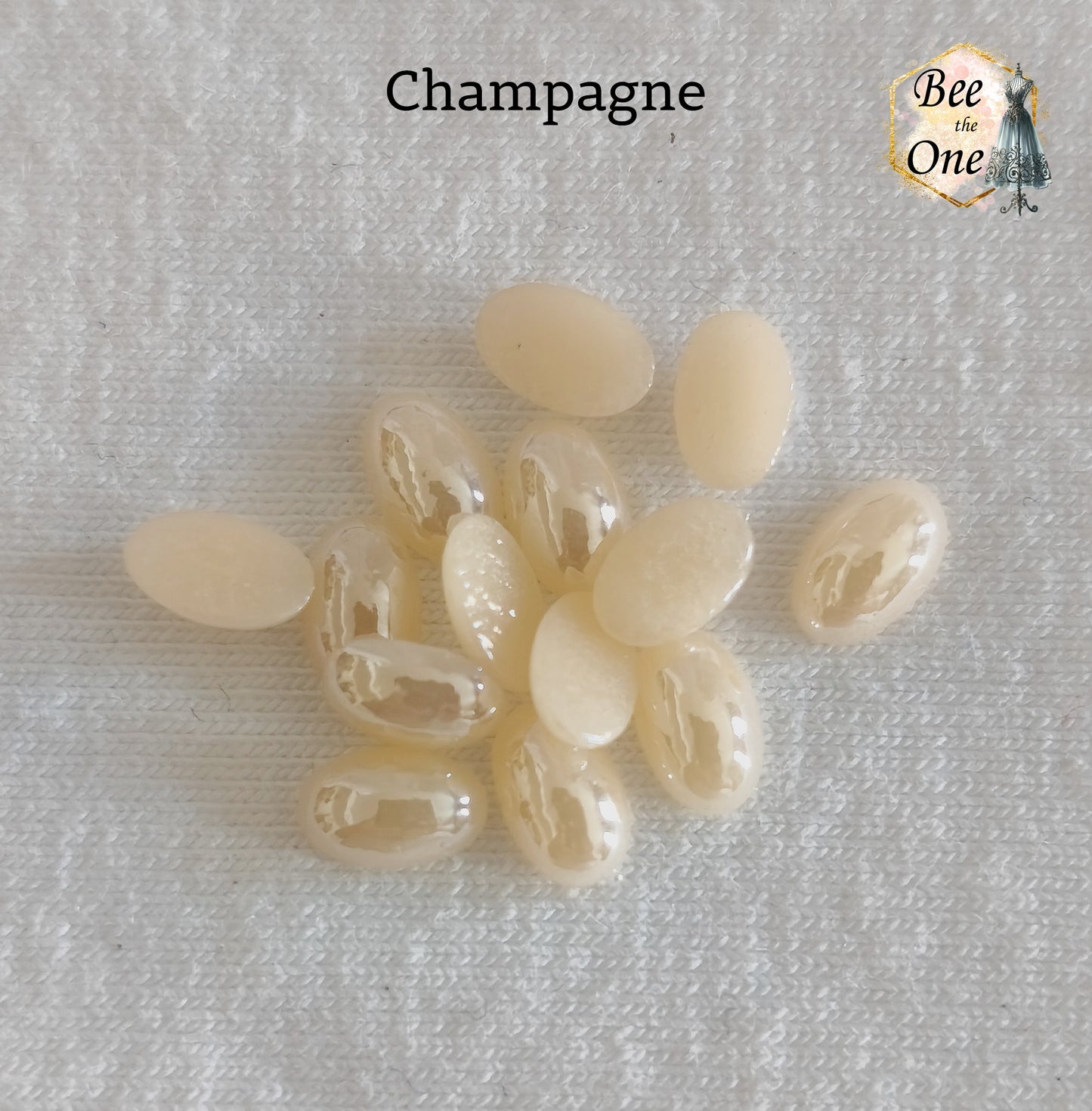 Mini cabochons ovales lisses de 6x4 mm en acrylique champagne, posés sur un fond blanc.