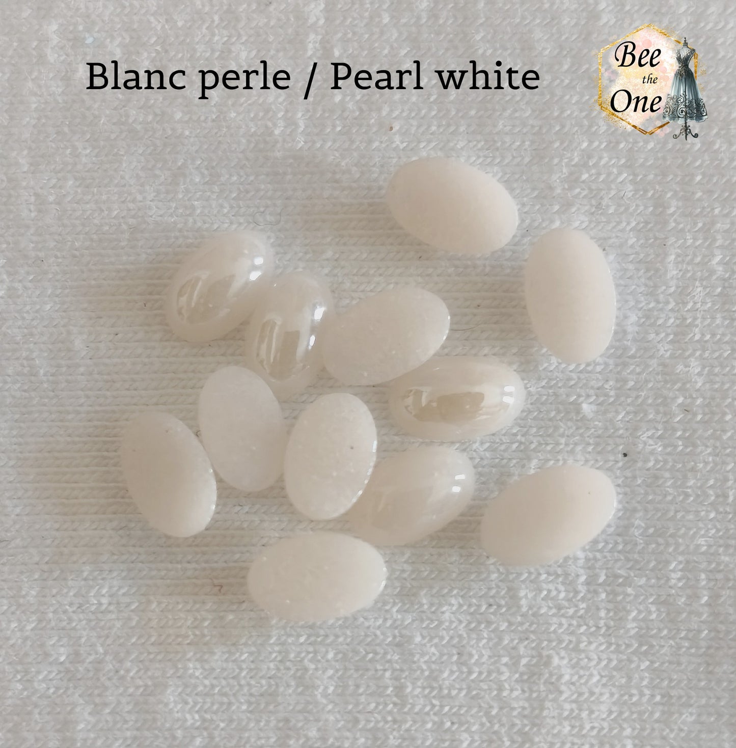 Mini cabochons ovales lisses de 6x4 mm en acrylique blanc perle, posés sur un fond blanc.