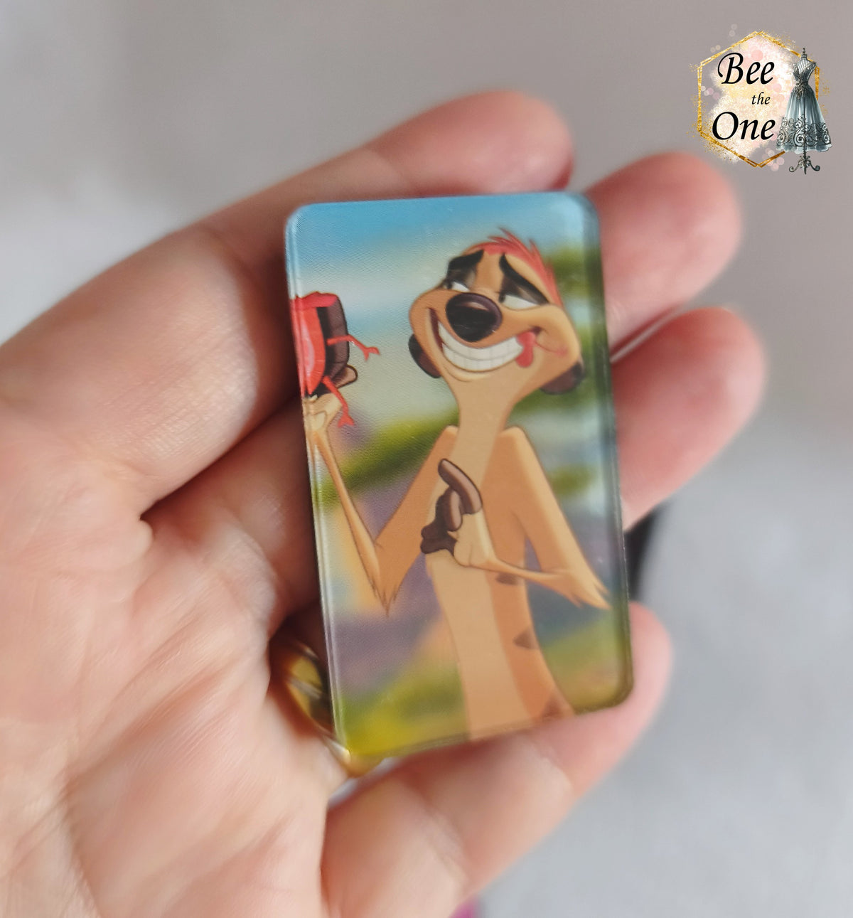 Magnets rectangulaires vertical à bords arrondis représentant Timon du Roi Lion, tenu dans une main, en gros plan