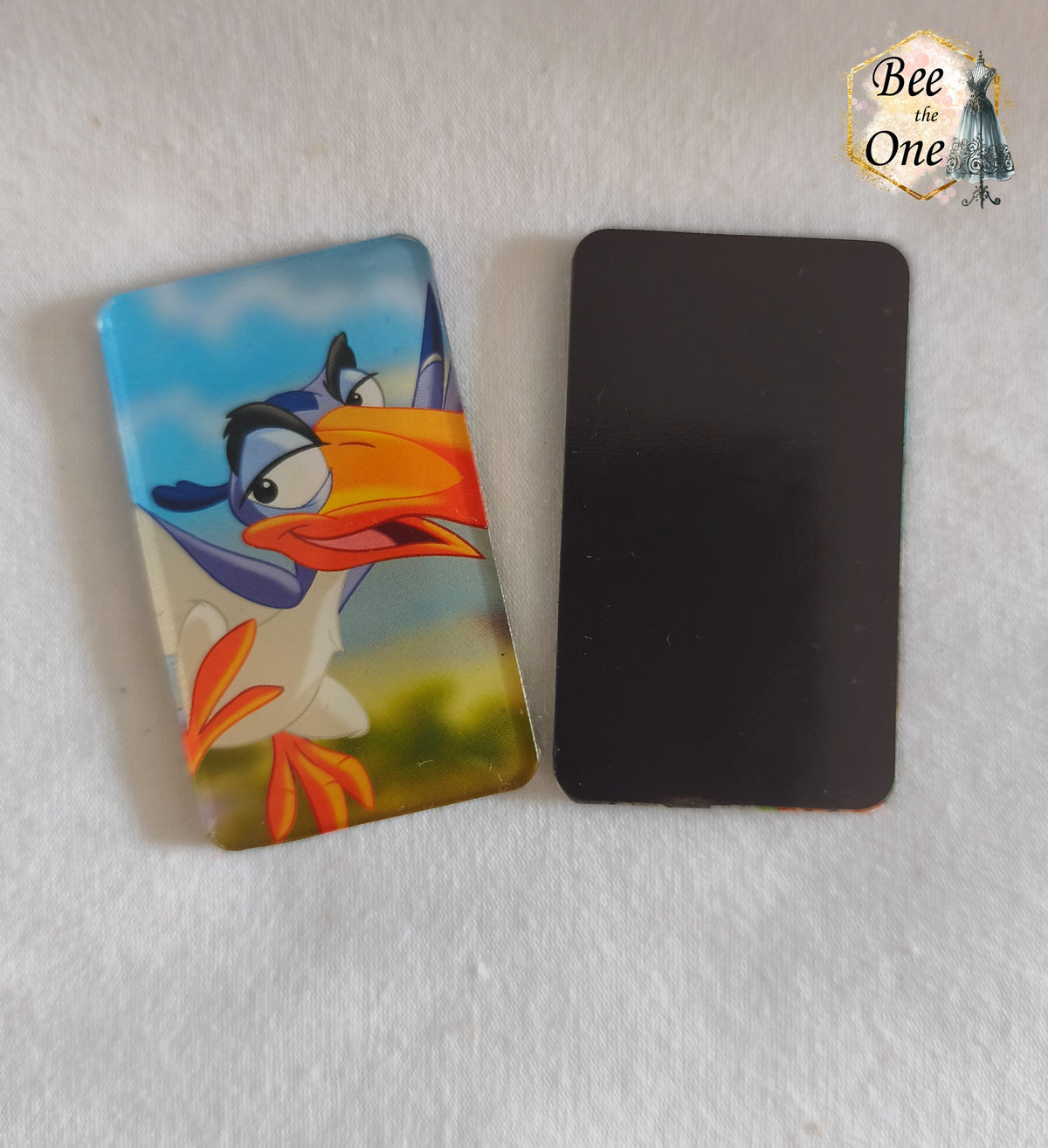 Magnets rectangulaires vertical à bords arrondis représentant Zazu du Roi Lion, tenu dans une main, en gros plan avec vue de devant et de dos