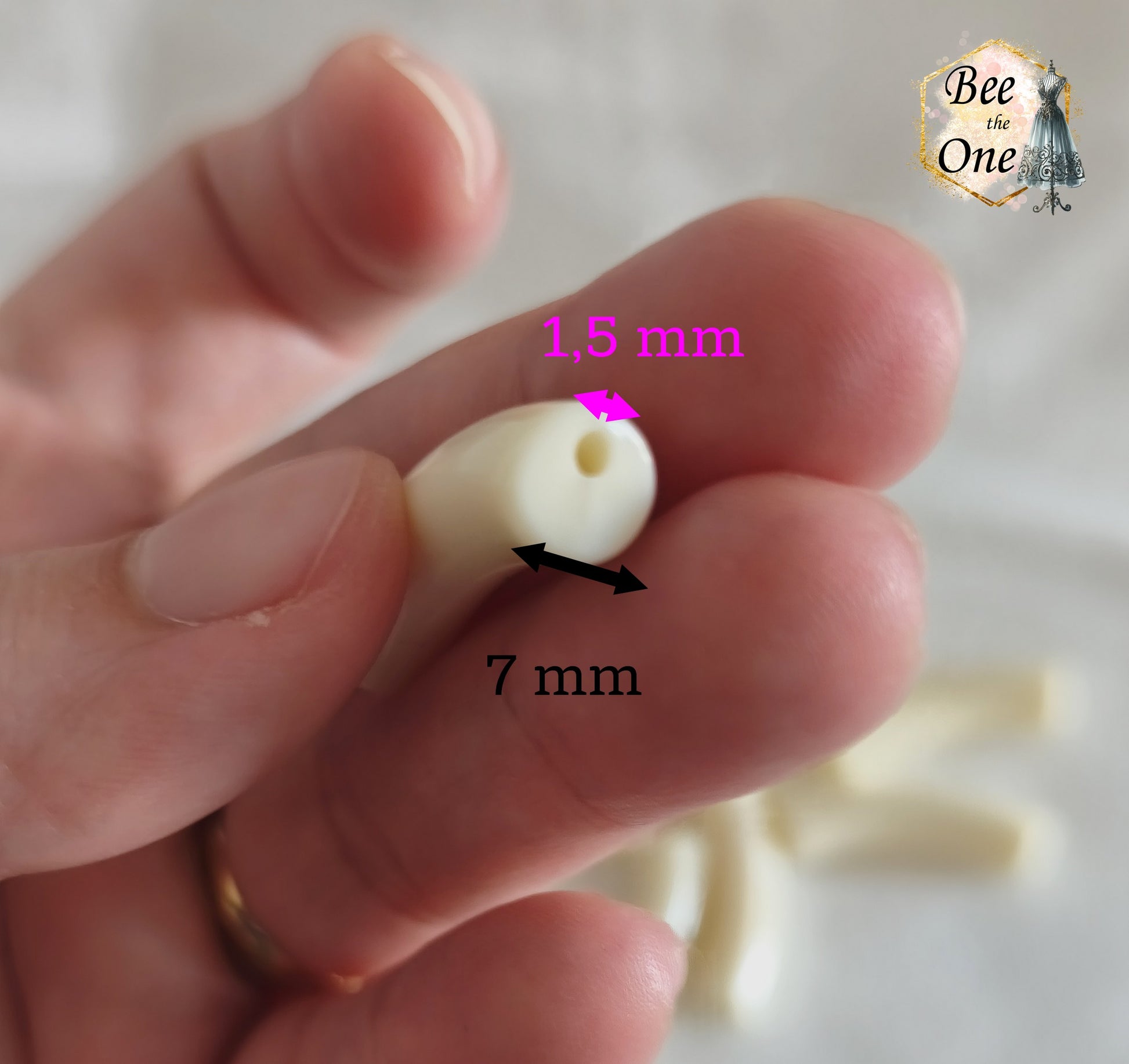 Perles tubes incurvées en acrylique couleur blanc crème unie mesurant 32x7 mm, disposées en demi-cercle sur un fond blanc texturé. Gros plan sur la tranche d'une perle