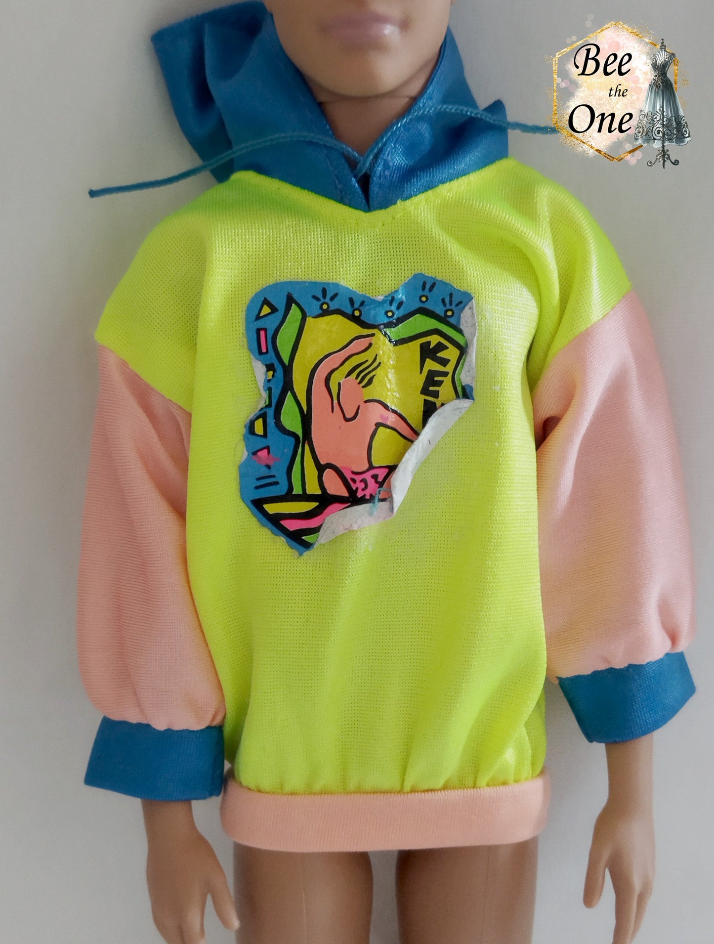 Pull pour poupée Ken en tissu mesh coloré, idéal pour une tenue décontractée ou sportive. Gros plan devant