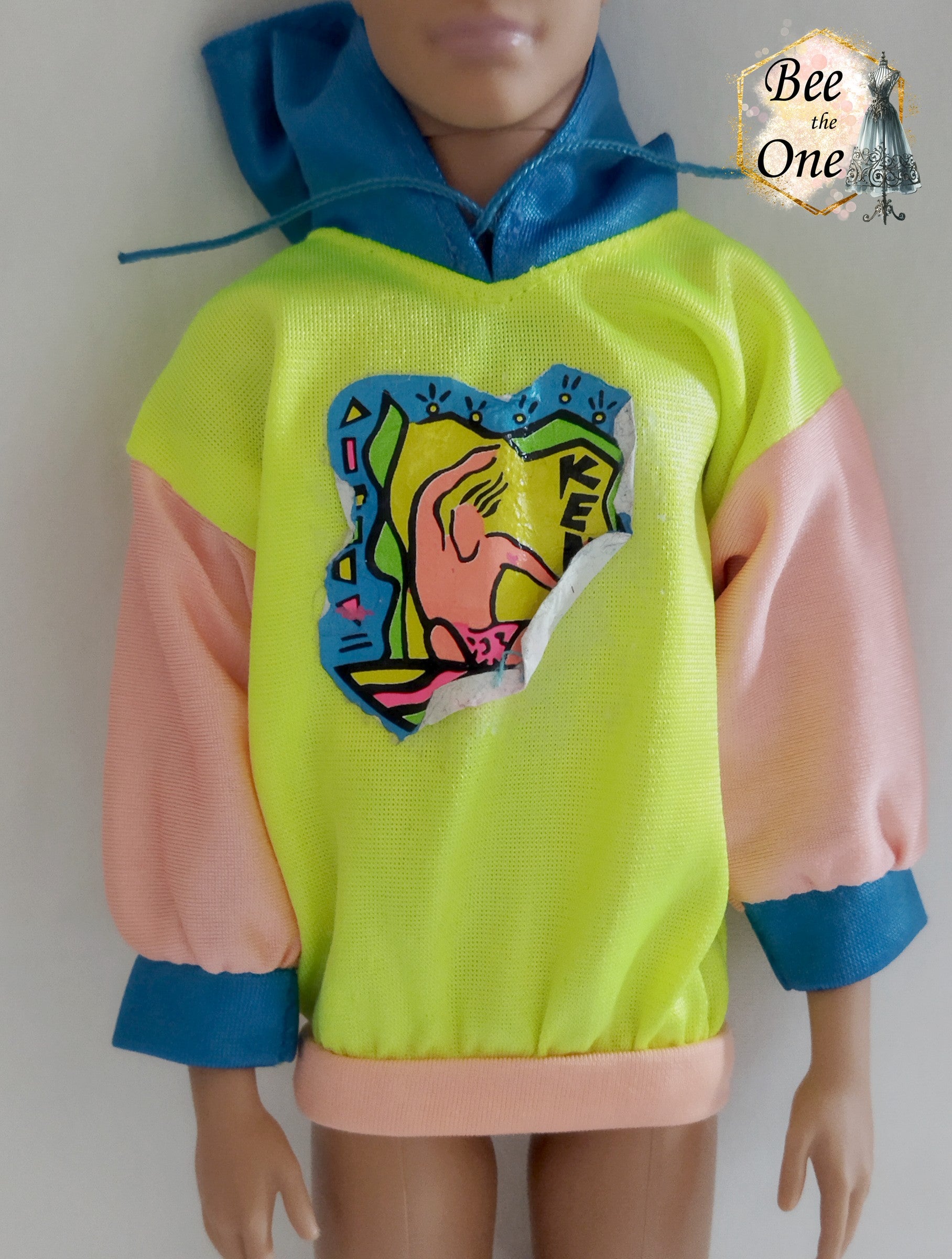 Pull pour poupée Ken en tissu mesh coloré, idéal pour une tenue décontractée ou sportive. Gros plan devant