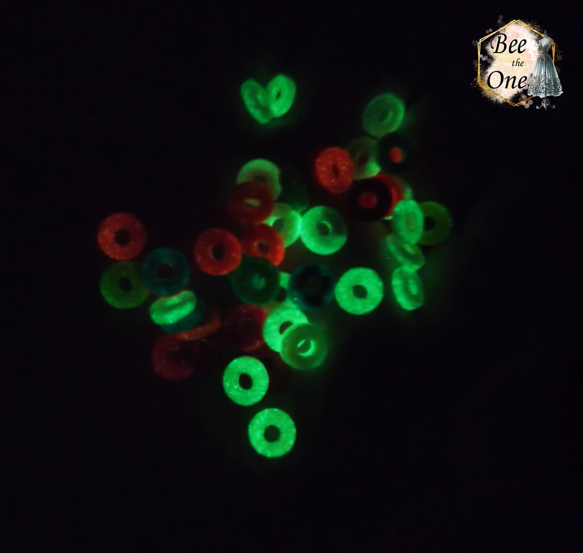 Lot de perles rondelles Heishi Katsuki en pâte polymère de 6 mm multicolores montrant leur effet phosphorescent vert et rouge brillant dans l'obscurité.