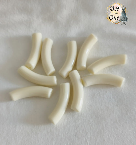Perles tubes incurvées en acrylique couleur blanc crème unie mesurant 32x7 mm, disposées en demi-cercle sur un fond blanc texturé.