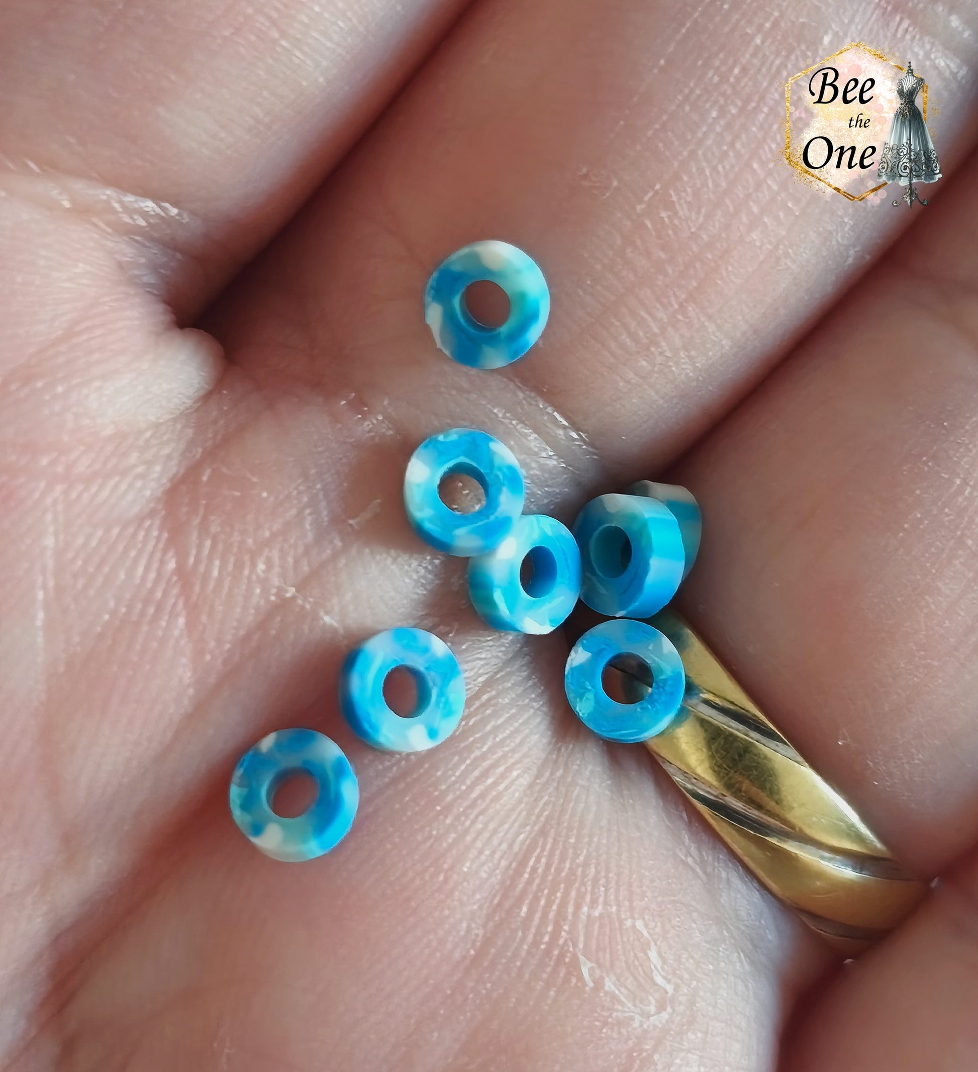 Petites perles rondelles Heishi Katsuki de 4 mm en pâte polymère, bleues. gros plan de quelques perle dans le creux d'une paume