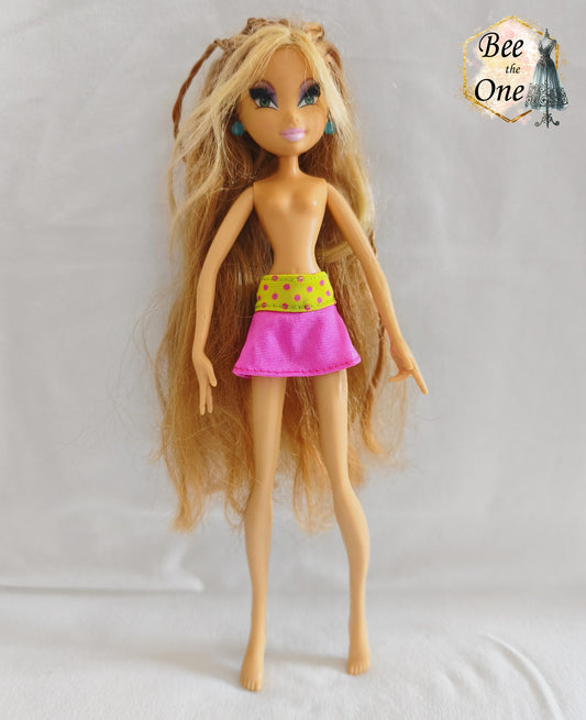 Mini-jupe rose avec large ceinture jaune fluo à pois roses pour poupée Winx Club, issue du modèle Flora Flutter Magic, portée par une poupée sur fond blanc