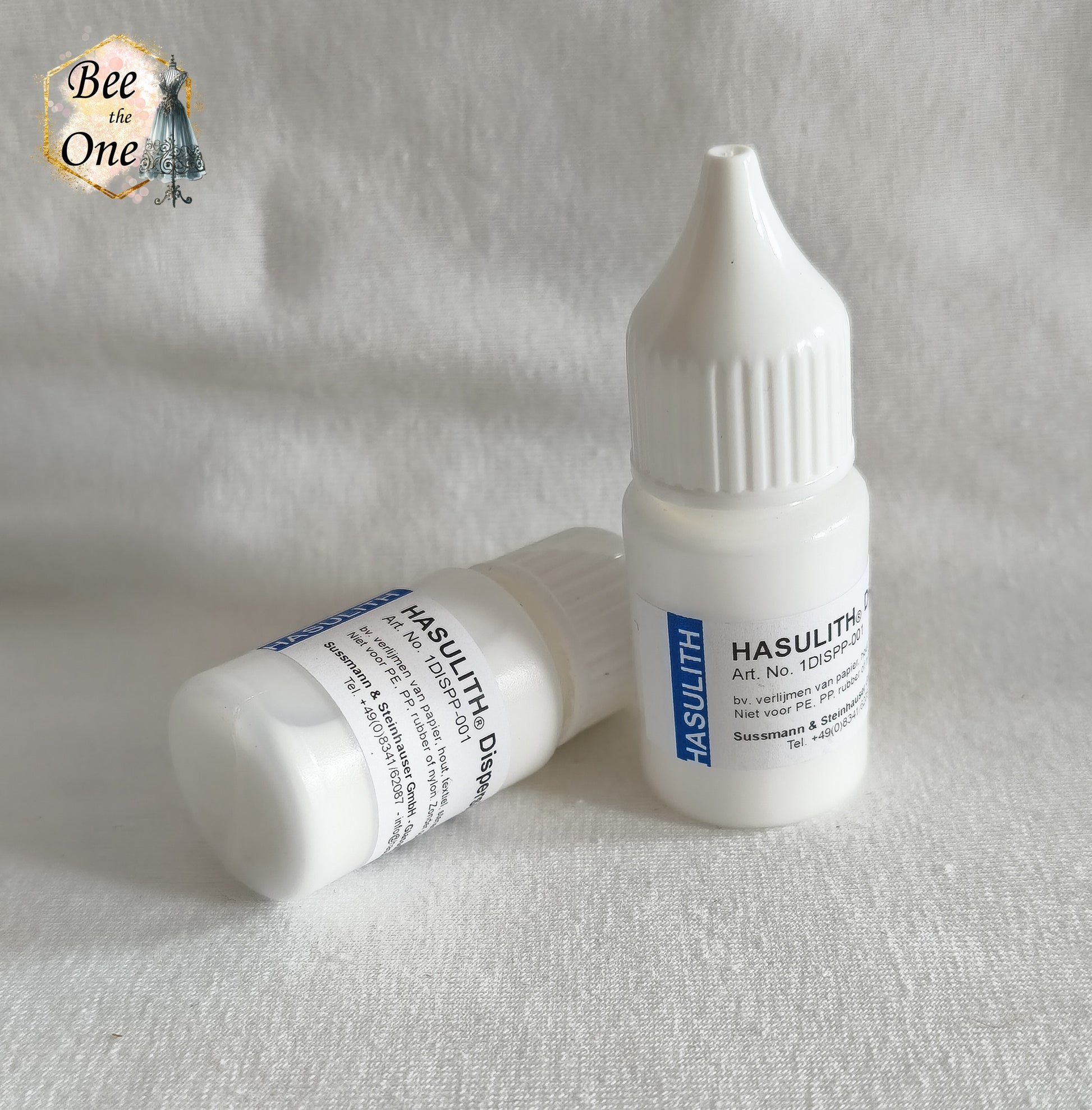 Deux flacons applicateurs de colle Hasulith Dispersion de 10 ml avec bouchons blancs, l'un debout et l'un couché, posés sur un fond blanc texturé