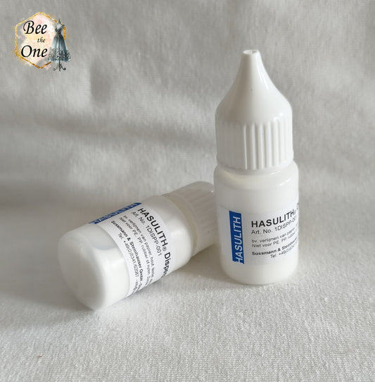 Deux flacons applicateurs de colle Hasulith Dispersion de 10 ml avec bouchons blancs, l'un debout et l'un couché, posés sur un fond blanc texturé