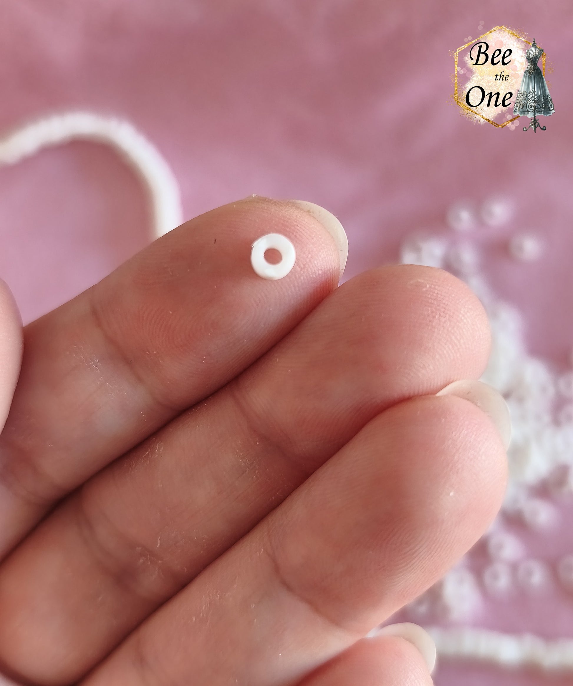 Petites perles rondelles Heishi Katsuki de 4 mm en pâte polymère, blanches. gros plan d'une perle sur le bout d'un doigt